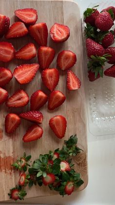 sliced strawberries on a cutting board next to water