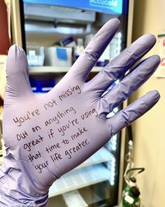 a gloved hand with writing on it in front of a tv screen and refrigerator