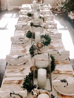 a long table with white plates and gold place settings