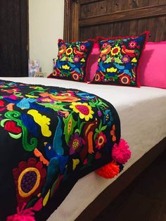 a bed with colorful pillows and blankets on it