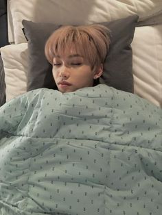 a boy sleeping in bed with his eyes closed