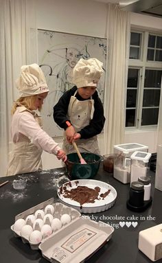 two children in chef's hats are making chocolate cake with utensils on the table