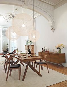 a dining room table with four chairs and a chandelier hanging from the ceiling