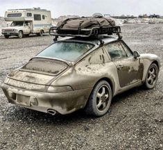 an old car with luggage strapped to it's roof is parked in the gravel