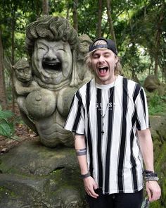 a man standing in front of a stone statue with his mouth open and tongue out