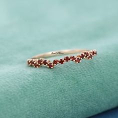 a gold ring with three small red stones on the side, sitting on top of a green cloth