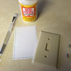 a white light switch plate sitting next to a glue bottle