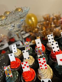 cupcakes with playing cards on them sitting on a table