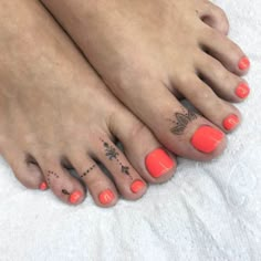 a woman's feet with tattoos and orange nail polishes on top of them