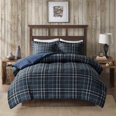 a bed with blue and white plaid comforter in a room next to a table