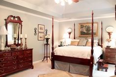 a bedroom with four poster bed, dresser and chair in the middle of the room