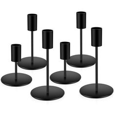 four black candlesticks sitting on top of each other in front of a white background