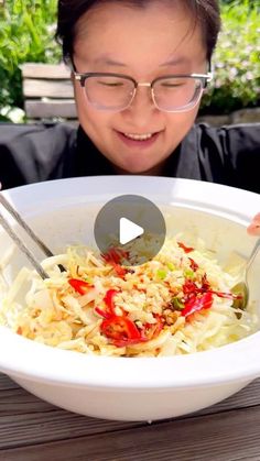 a woman with glasses is looking at a bowl of food that has rice and vegetables in it