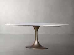 an oval table with a white marble top and gold metal base, against a gray background