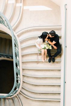 a man and woman sitting on top of a set of stairs next to each other