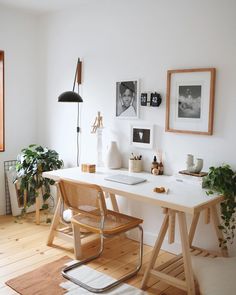 a white desk with some plants and pictures on the wall