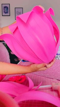 a woman is making pink flowers out of plastic cups and ribbones on a table