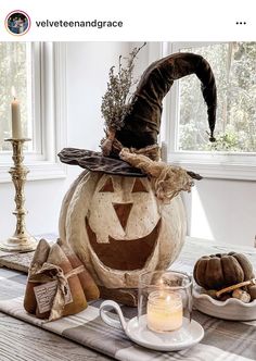 a decorated pumpkin sitting on top of a table next to a cup and saucer