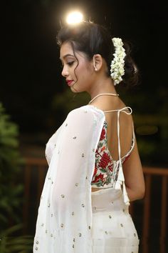 a woman in a white sari with flowers in her hair and wearing a flower in her hair