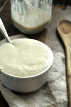 a white bowl filled with batter next to a wooden spoon on top of a table