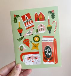 a hand holding up a christmas card with stickers on it