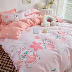 a bed with pink comforters and teddy bears on it