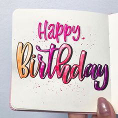 someone holding up a birthday card with the words happy birthday written in pink and orange