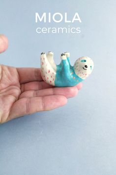 a hand holding a tiny blue and white animal figurine