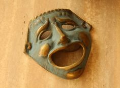 a green mask sitting on top of a wooden table with holes in it's face