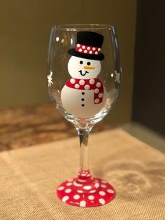 a wine glass with a snowman painted on it