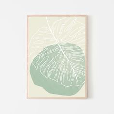 a green and white leaf print hanging on a wall next to a wooden framed object