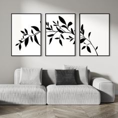 two black and white paintings hanging on the wall above a couch in a living room