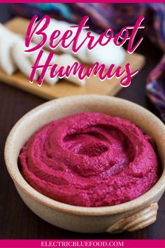 a wooden bowl filled with beet hummus next to garlic