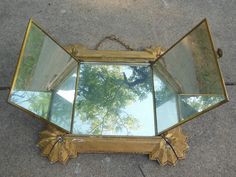 a mirror that is sitting on the ground next to a tree and some concrete flooring