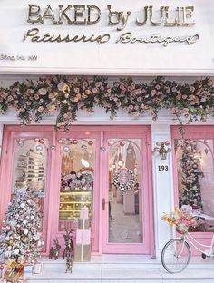 a store front with pink doors and flowers on it