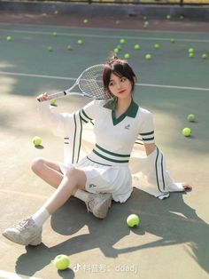 a woman sitting on the ground holding a tennis racquet and ball in her hand