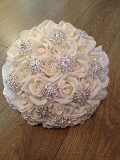 a bridal bouquet with white roses and crystal brooches on a wooden floor