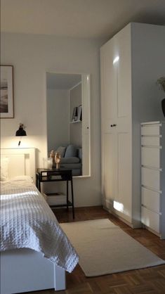 a bedroom with white furniture and wood floors