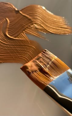 a close up of a paint brush with some brown liquid on it's side