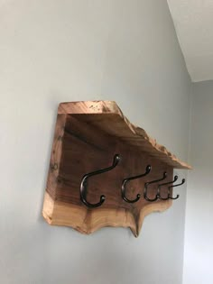 there is a wooden shelf with hooks on it and two fish hooks attached to the wall