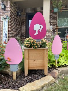 pink and gray garden decorations in front of a brick house with flowers on the side