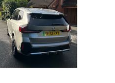 the rear end of a silver car parked in front of a house on a street