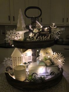 a three tiered tray with christmas decorations and lights on it in a kitchen area