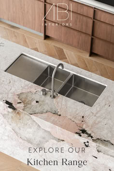 a marble sink with two faucets in the middle and wood cabinets behind it