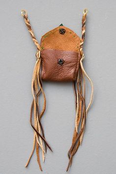 a brown leather purse hanging on a wall with two braids attached to the front