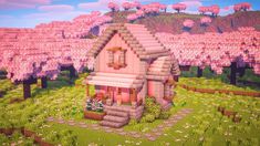 a small pink house sitting in the middle of a lush green field with lots of trees