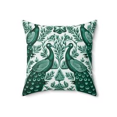 a green and white pillow with two peacocks on it