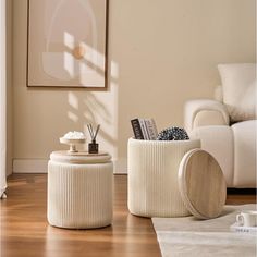 a living room with two white stools and a coffee table in front of a painting