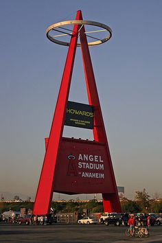 an angel stadium sign in the middle of a parking lot with people walking around it