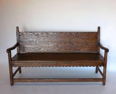 an old wooden bench sitting against a white wall with no one on it's legs